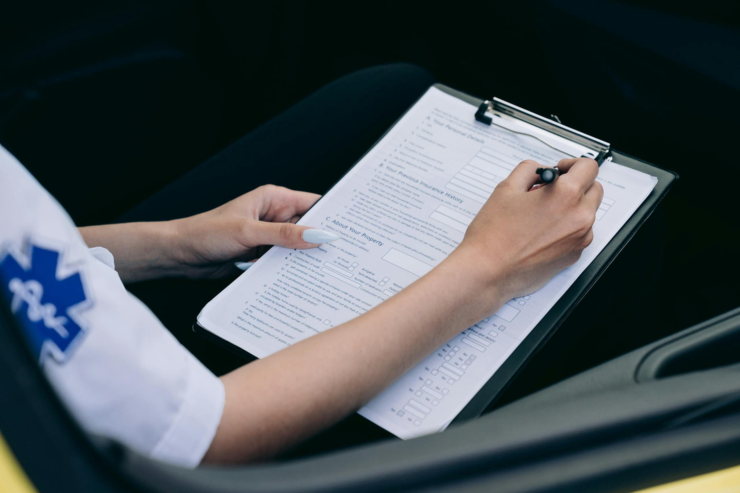 Close-up of a paramedic taking notes on a clipboard in a car.